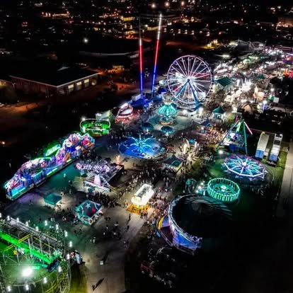 Aerial night view of a county fair midway lit up with rides and lights