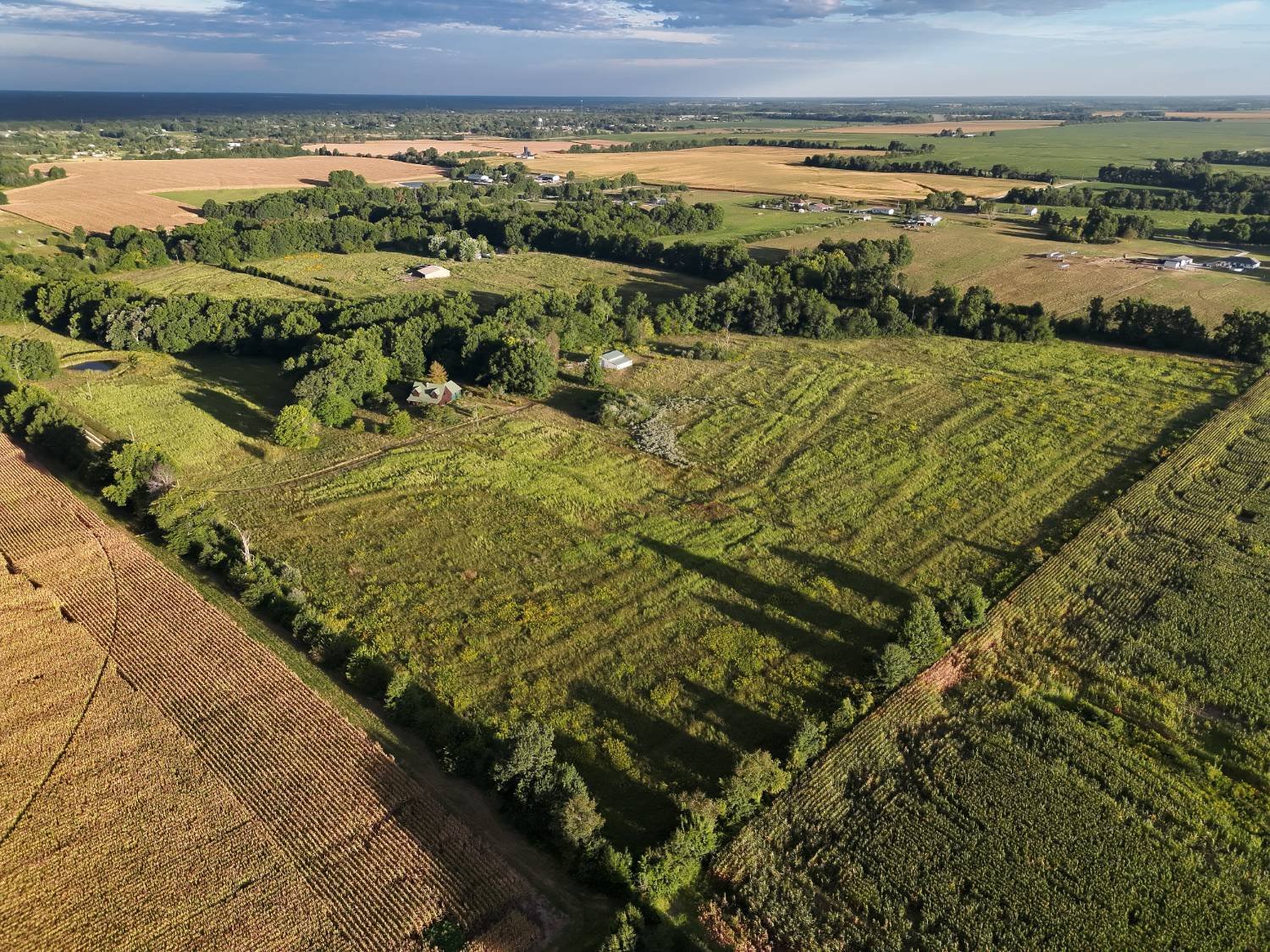 Wide aerial view of a Missouri property with farmland, timber, and a farmstead