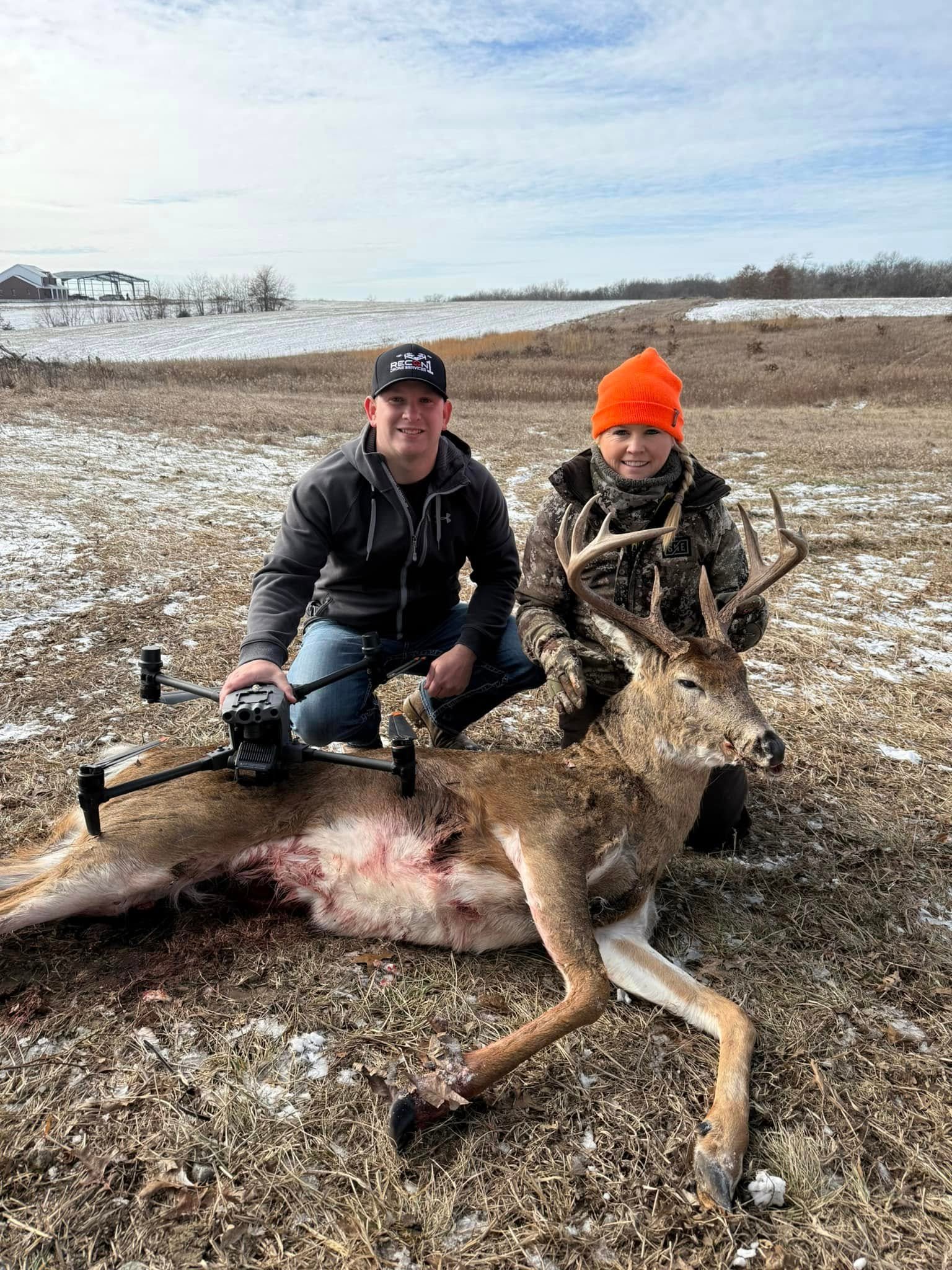 Recon1 pilot and hunter with a recovered buck in a snowy field, drone in hand