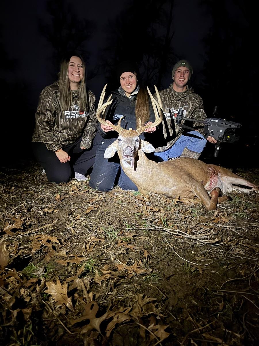 Recon1 team in branded jackets with a client and recovered buck at night